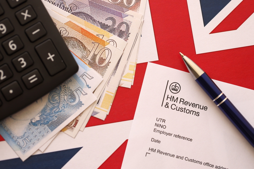 HM Revenue and Customs header on tax return form blank with money, calculator and pen close up