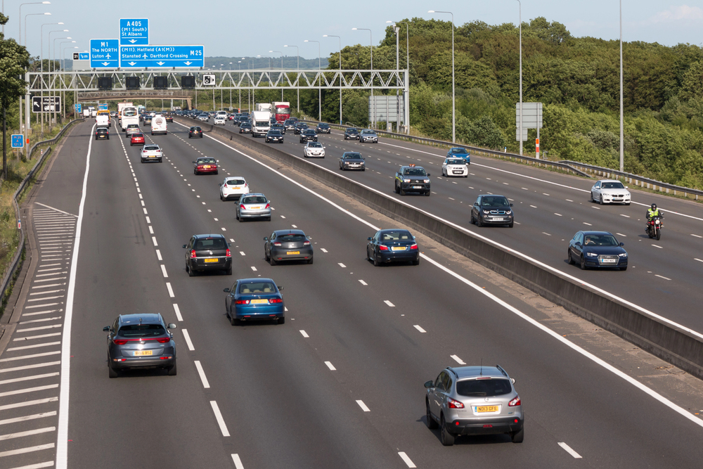 Simple and easy consultant accounting Busy multi-lane UK motorway with cars and trucks, overhead signs indicating M1, M25, and A405 routes